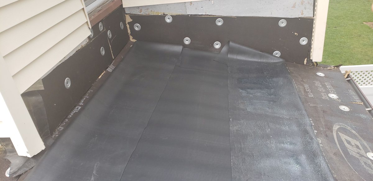 Black EPDM rubber membrane installed on a flat roof between two white-sided walls